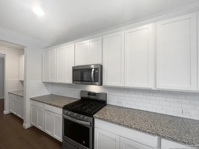 a kitchen with granite countertop a sink stove and microwave