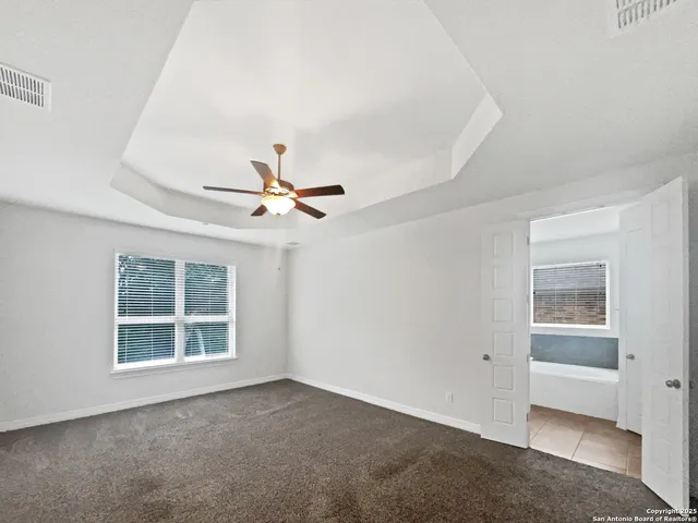 an empty room with windows and fan