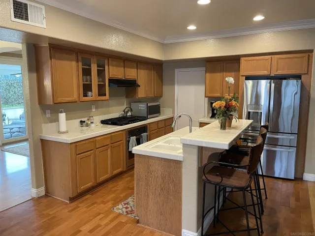 a kitchen with stainless steel appliances kitchen island granite countertop a sink stove and refrigerator
