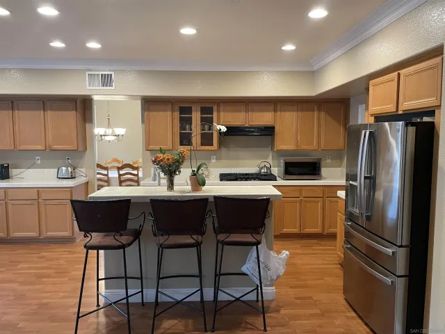 a kitchen with a refrigerator a sink dishwasher and a dining table with wooden cabinet