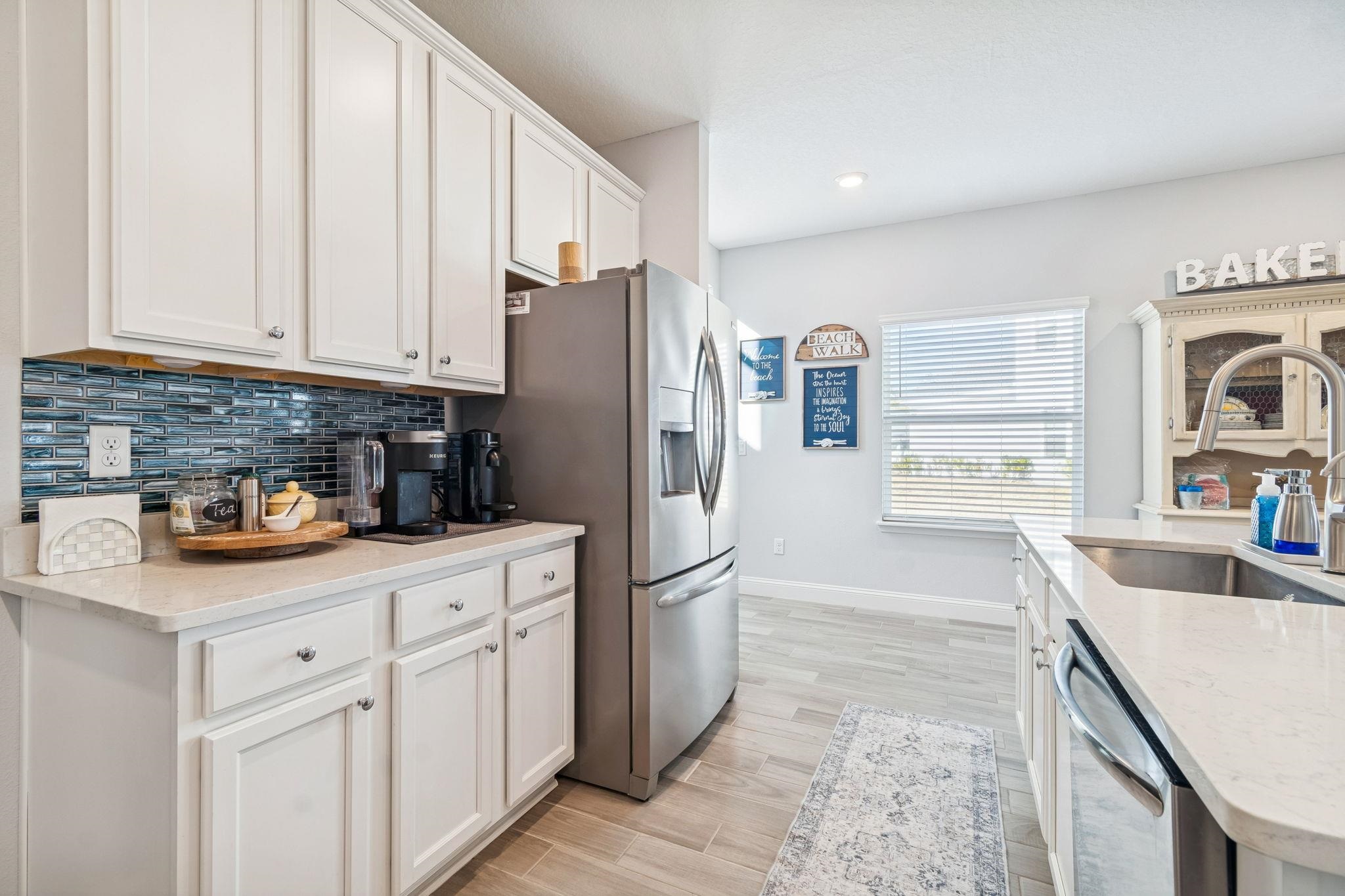 262 Killarney Avenue St. Johns, FL 32259 - Photo 10 of 100 Kitchen featuring white cabinetry, appliances with stainless steel finishes, light stone countertops, wood tiled floors, and decorative backsplash