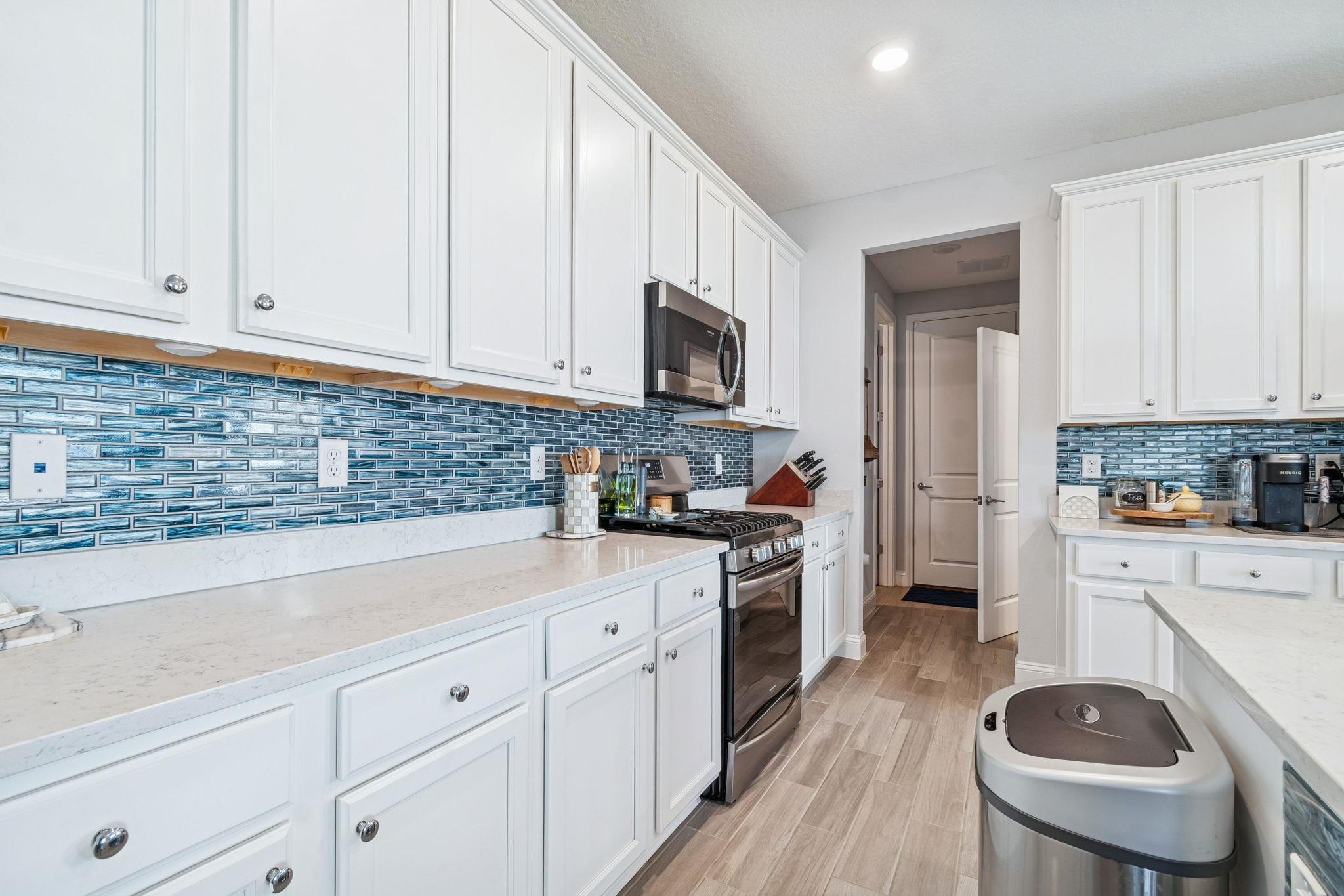 262 Killarney Avenue St. Johns, FL 32259 - Photo 13 of 100 Kitchen featuring stainless steel appliances, white cabinets, light stone countertops, light wood-style floors, and backsplash