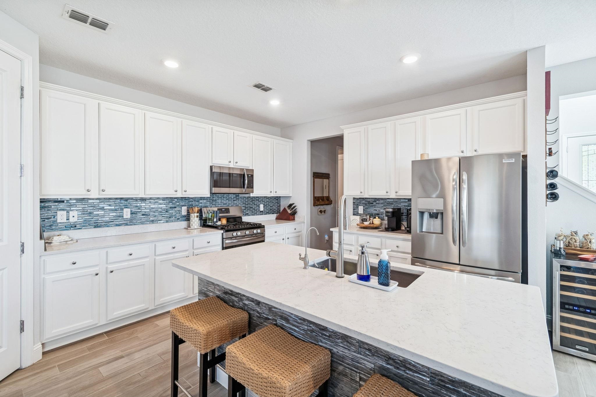 262 Killarney Avenue St. Johns, FL 32259 - Photo 17 of 100 Kitchen featuring a breakfast bar area, appliances with stainless steel finishes, light stone countertops, white cabinets, and a center island with sink