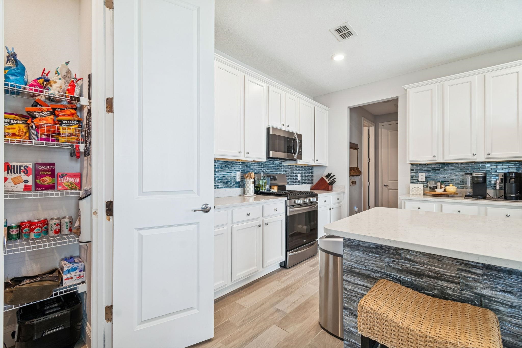 262 Killarney Avenue St. Johns, FL 32259 - Photo 18 of 100 Kitchen featuring appliances with stainless steel finishes, white cabinets, light wood finished floors, light stone countertops, and recessed lighting