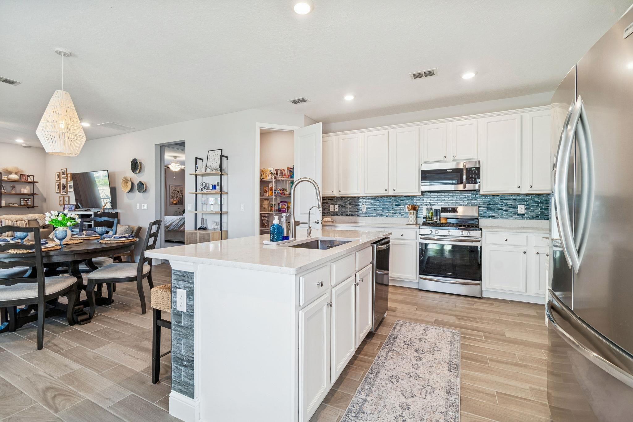 262 Killarney Avenue St. Johns, FL 32259 - Photo 100 of 100 Kitchen with stainless steel appliances, open floor plan, a center island with sink, white cabinets, and light stone counters