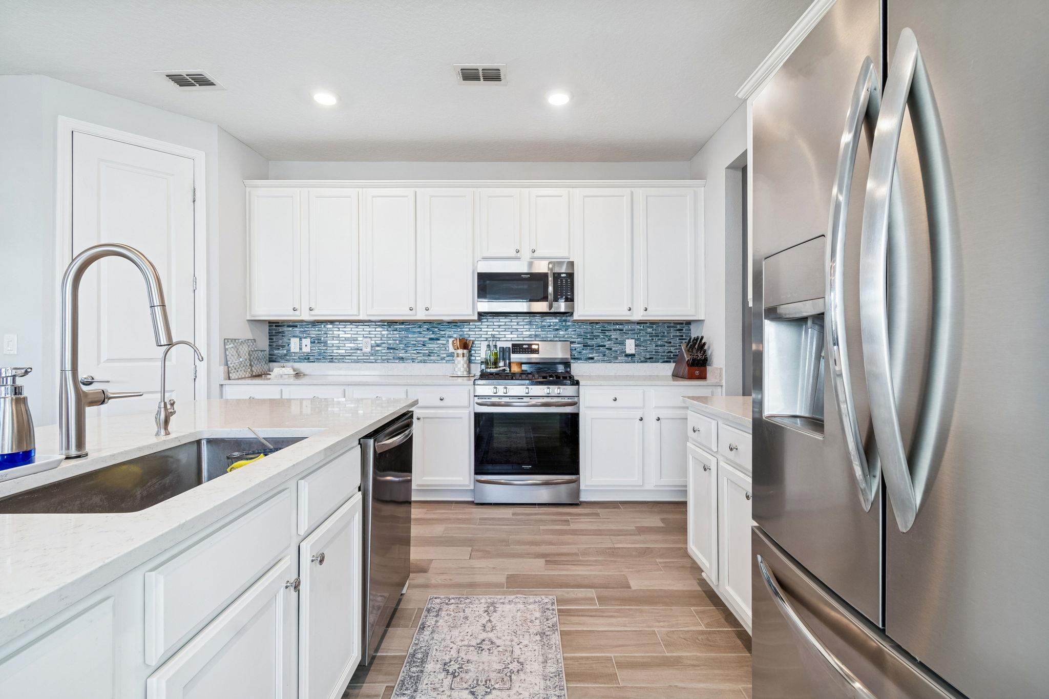262 Killarney Avenue St. Johns, FL 32259 - Photo 8 of 100 Kitchen with stainless steel appliances, white cabinetry, wood finish floors, light stone countertops, and recessed lighting