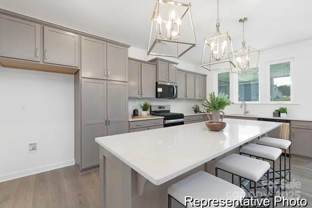 a kitchen with stainless steel appliances kitchen island granite countertop a refrigerator a sink dishwasher a dining table and chairs with wooden floor