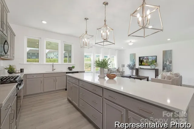 a large white kitchen with a large island oven a stove a sink a dining table and chairs