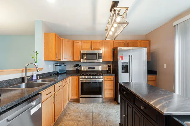 a kitchen with stainless steel appliances granite countertop a sink a stove cabinets counter space and a window