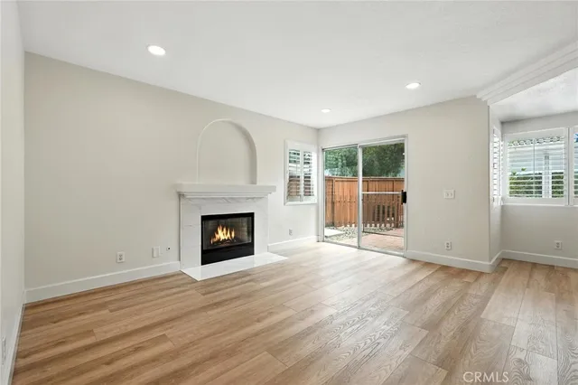 an empty room with wooden floor fireplace and windows