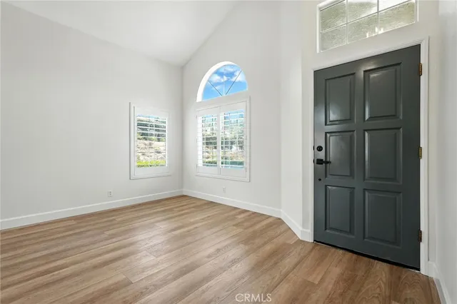 an empty room with wooden floor cabinet and windows