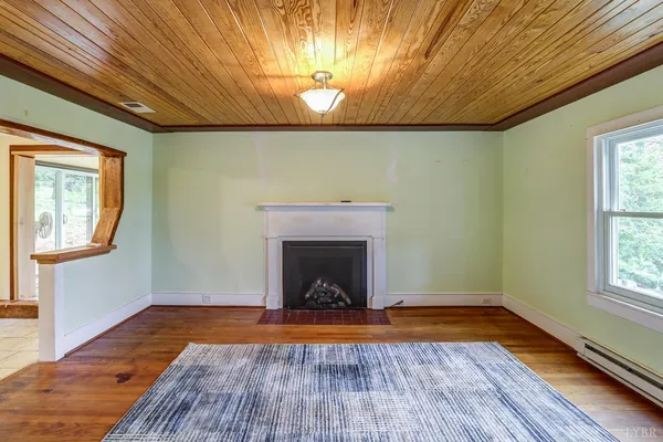 a view of an empty room with window and wooden floor