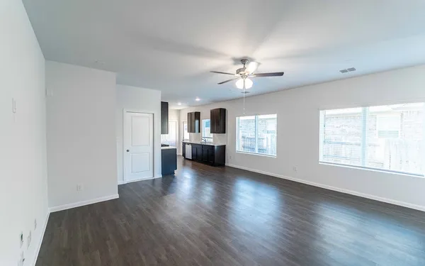 an empty room with wooden floor chandelier and windows