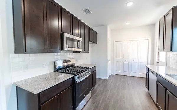 a kitchen with granite countertop stainless steel appliances a stove top oven and wooden floor