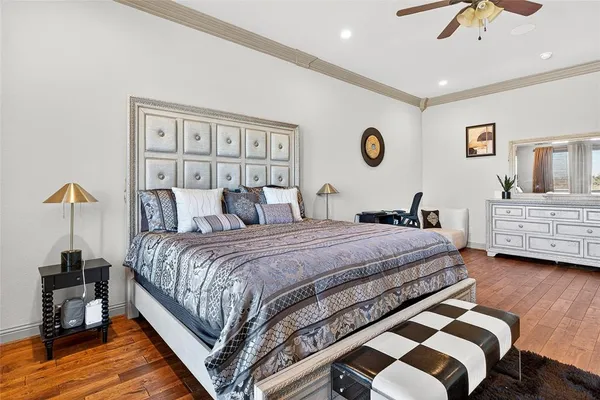 a bedroom with a bed a dresser and wooden floor