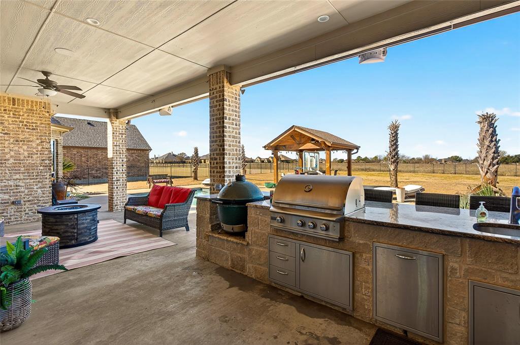 12099 Briargrove Lane Forney, TX 75126 - Photo 28 of 38 Fenced backyard featuring ceiling fan, an outdoor kitchen with living area, a patio area, and an outdoor fire pit
