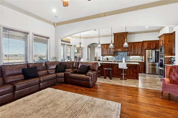 a living room with furniture kitchen view and a wooden floor