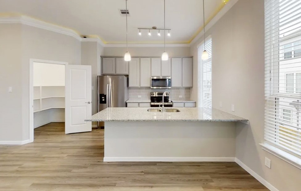 5609 Mina Way Houston, TX 77081 - Photo 12 of 12 a view of kitchen with stainless steel appliances granite countertop a stove top oven a refrigerator white cabinets and couches with wooden floor