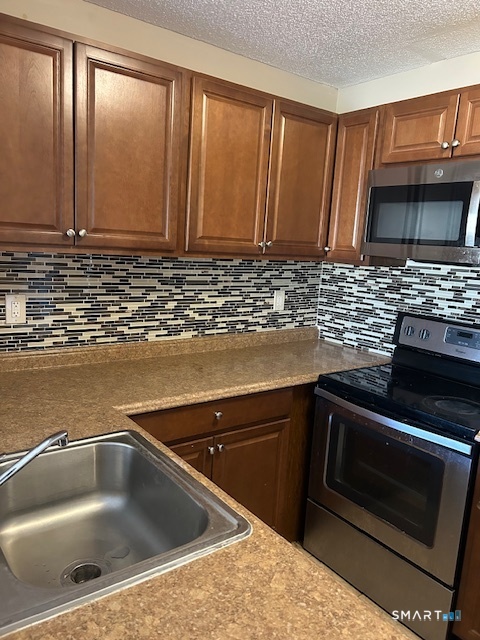 175 Mill Pond Road, Unit 214 Hamden, CT 06514 - Photo 3 of 22 a kitchen with granite countertop a sink stove and cabinets
