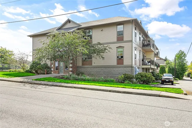 a view of a house with a yard and a large tree