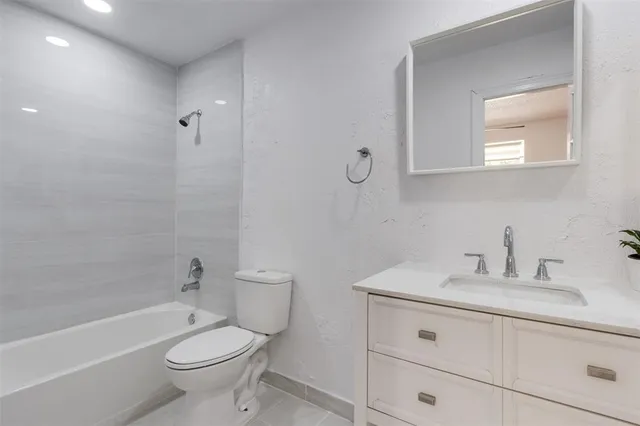 a bathroom with a granite countertop sink a toilet and with mirror