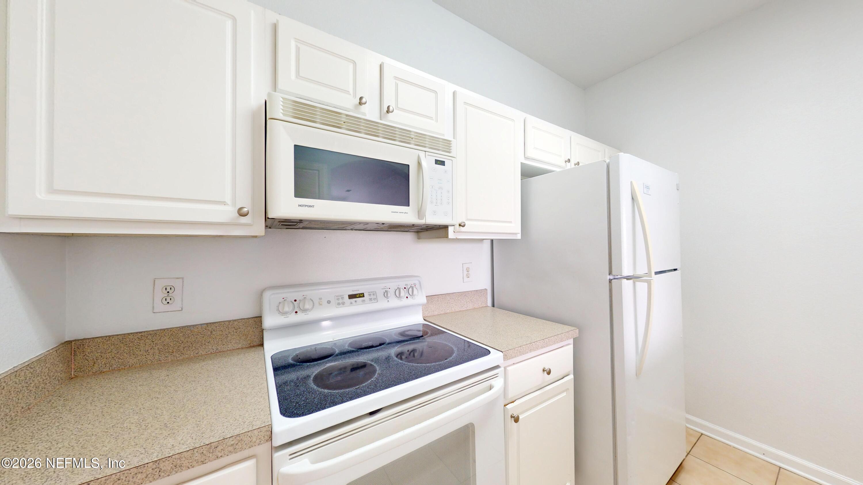 7990 Baymeadows Road East, Unit 912 Jacksonville, FL 32256 - Photo 6 of 25 a kitchen with stainless steel appliances white cabinets and a refrigerator
