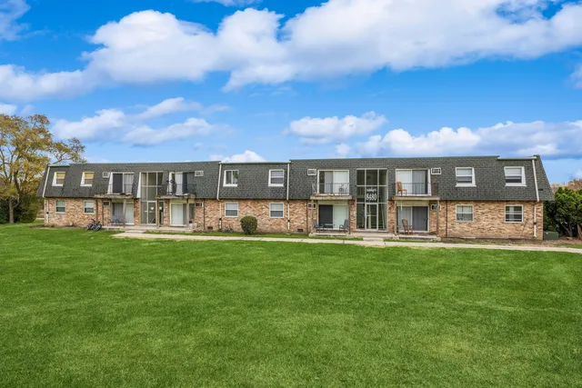 a view of a house next to a big yard and large trees