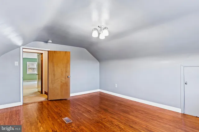 an empty room with wooden floor cabinet and windows