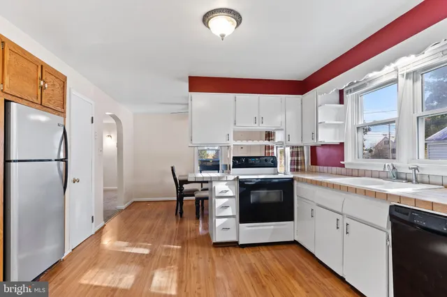 a kitchen with stainless steel appliances a stove a sink dishwasher a refrigerator and a dining table with wooden floor