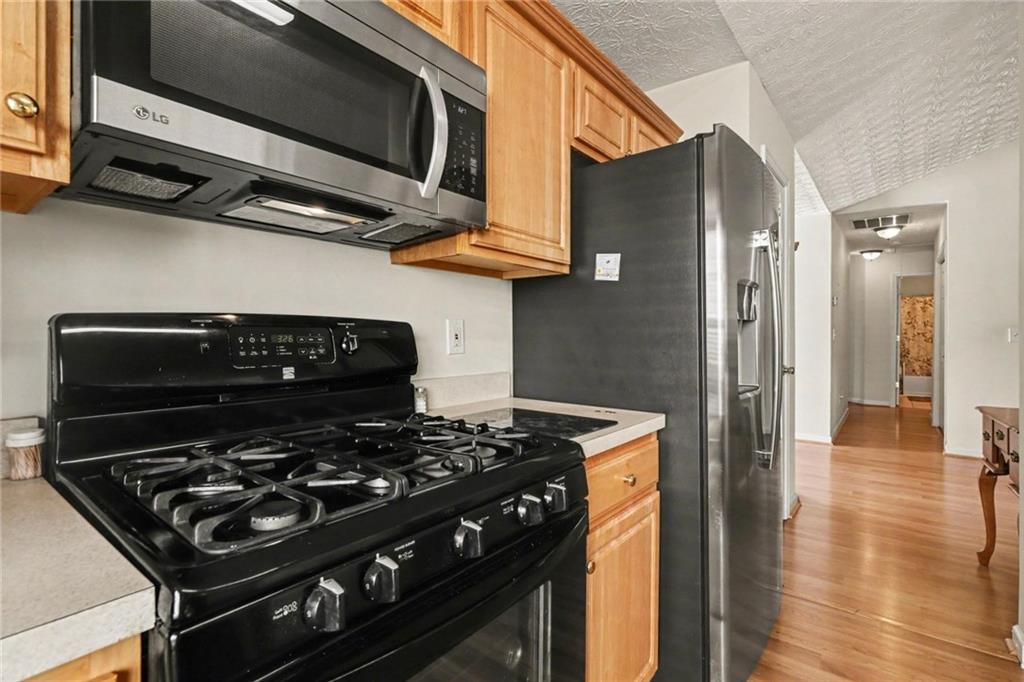 304 Allegheny Avenue Dallas, GA 30132 - Photo 10 of 30 a kitchen with stainless steel appliances granite countertop a stove and a wooden floor
