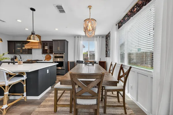 a dining room with wooden floor a chandelier a wooden table and chairs