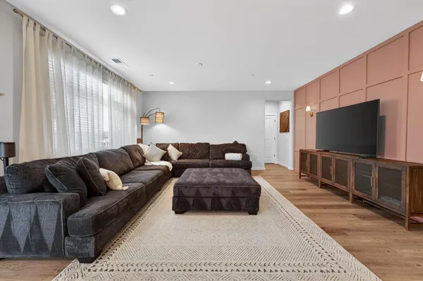 a living room with furniture a flat screen tv and a refrigerator