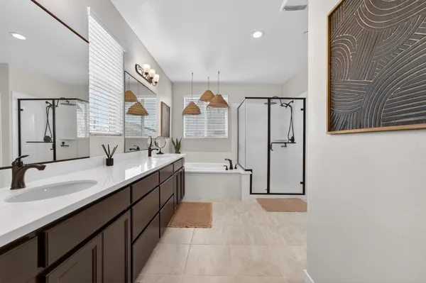 a bathroom with a tub double vanity sink and a large mirror