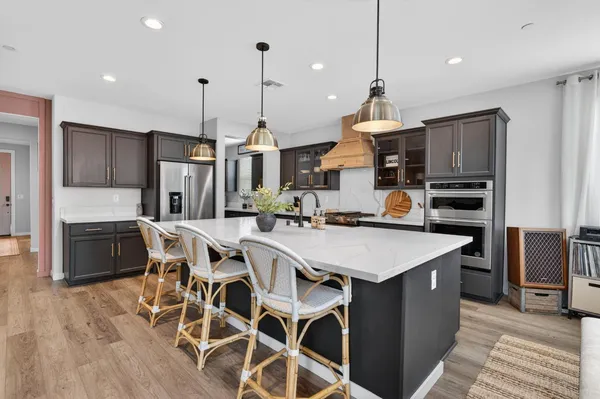 a kitchen with stainless steel appliances kitchen island granite countertop a stove a sink and a wooden floors