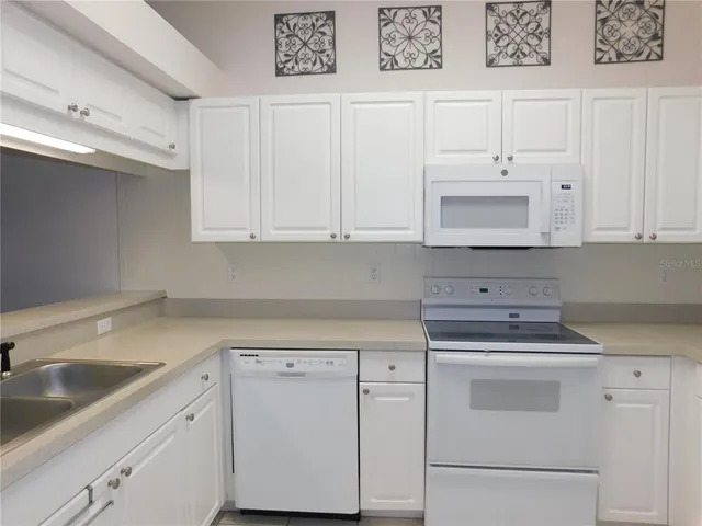 a kitchen with white cabinets and white appliances