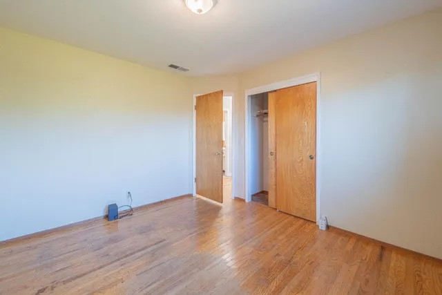 an empty room with wooden floor and closet