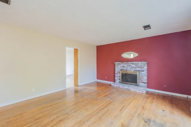 a view of empty room with wooden floor and fireplace