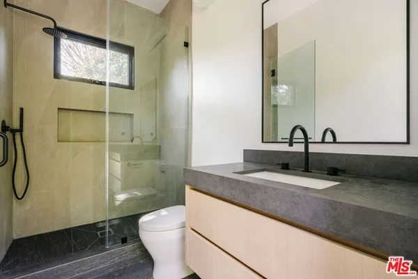 a bathroom with a granite countertop sink a toilet and shower