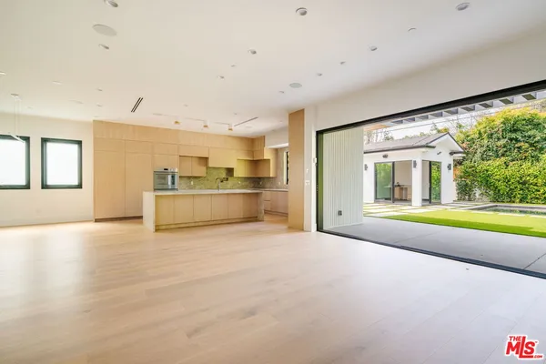 a view of an empty room with a window and kitchen view