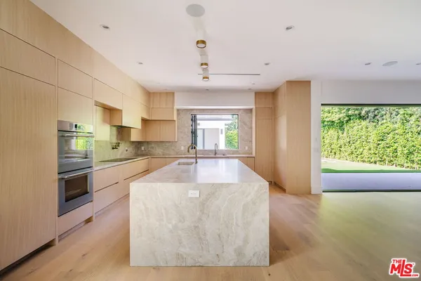 a large kitchen with kitchen island a large counter top space a sink stainless steel appliances and cabinets