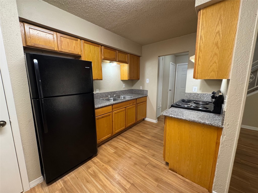4902 West Wind Trail, Unit 104 Austin, TX 78745 - Photo 5 of 18 a kitchen with granite countertop stainless steel appliances a refrigerator a stove a sink and a window