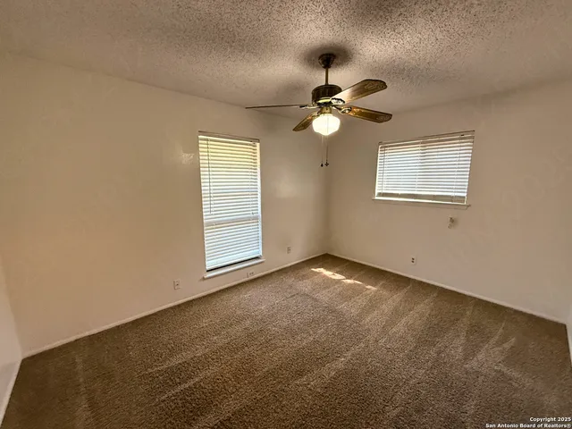 an empty room with windows and fan