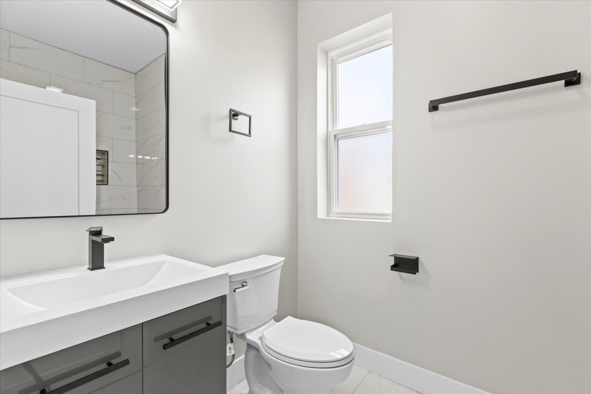 6128 South Rhodes Avenue, Unit 2 Chicago, IL 60637 - Photo 10 of 12 a bathroom with a toilet a sink a mirror and a window