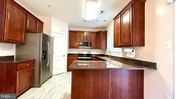 a kitchen with granite countertop wooden cabinets a stove top oven a granite counter space and stainless steel appliances