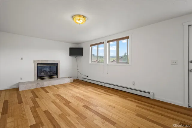a view of empty room with wooden floor and fireplace
