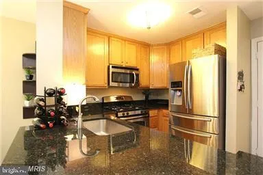 a kitchen with a refrigerator a stove and a sink with wooden floor