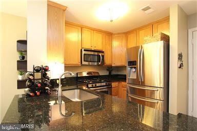 11864 Breton Court, Unit 14A Reston, VA 20191 - Photo 9 of 26 a kitchen with a refrigerator a stove and a sink with wooden floor