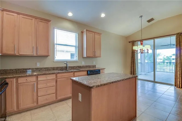 a kitchen with granite countertop a sink window and cabinets