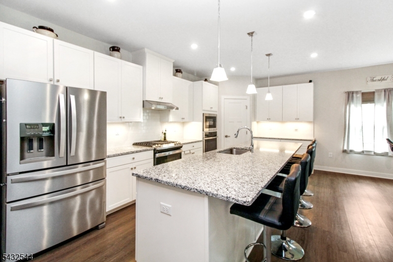 21 Harris Hawk Road Washington, NJ 07882 - Photo 6 of 26 a kitchen with stainless steel appliances granite countertop a sink a stove a refrigerator and island with wooden floor