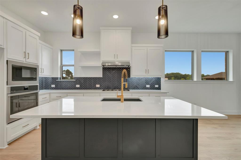 1856 Lightner Road Van Alstyne, TX 75495 - Photo 12 of 33 Modern kitchen island featuring a light-toned countertop and contrasting dark cabinetry